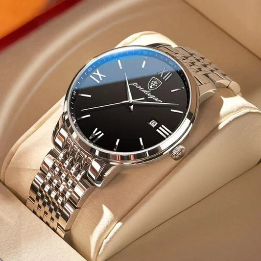 A silver and black quartz watch with a metal band and a luminous hands, displayed on a tan surface.

