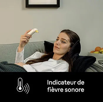 Woman using a device on her forehead with text indicating fever detection, sitting on a couch.

