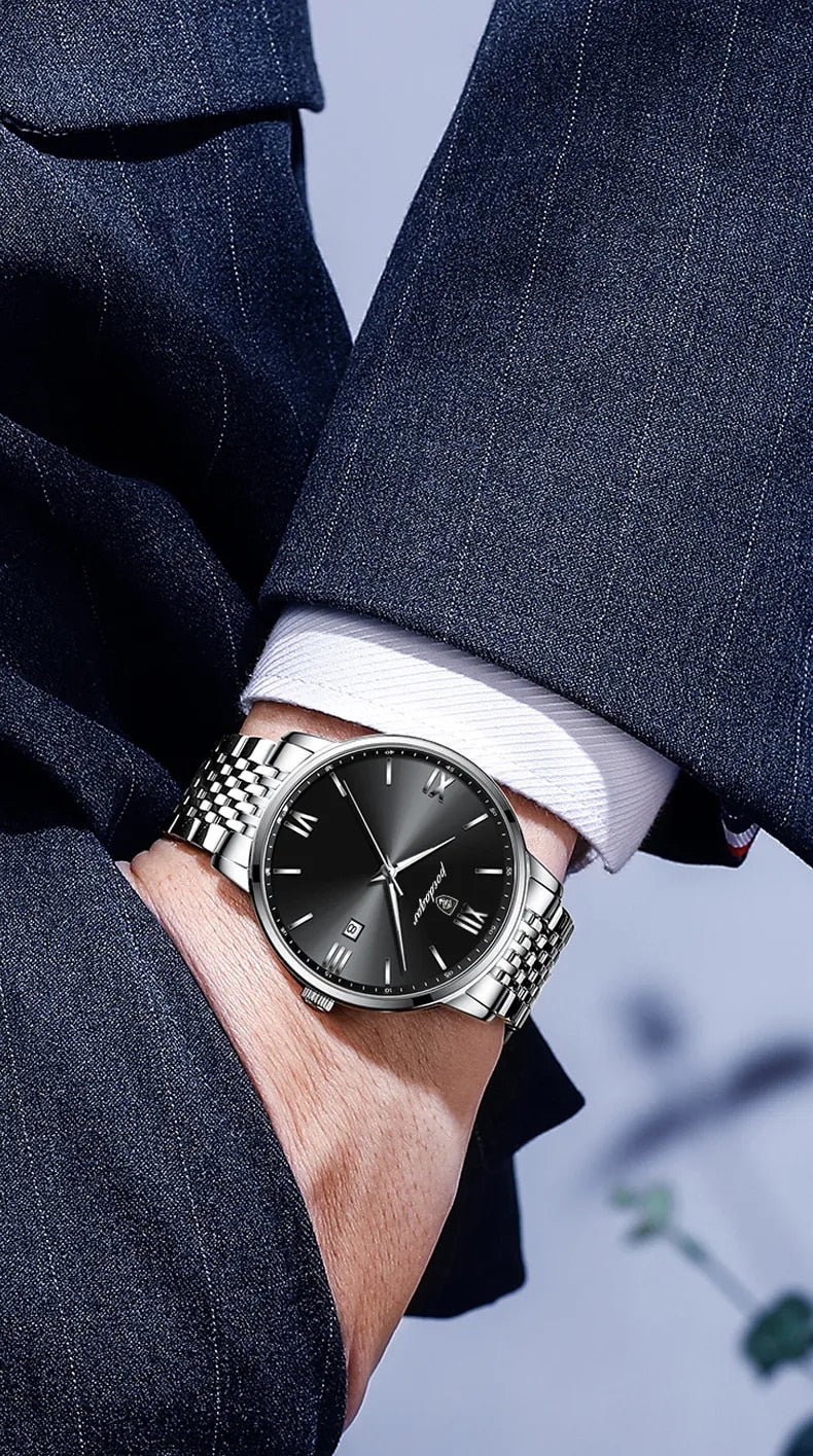 A silver and black quartz watch with a metal band and a luminous hands, displayed on a tan surface.

