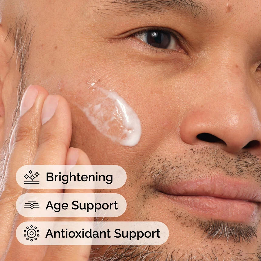 Man applying cream to his face with text indicating brightening, age support, and antioxidant support.

