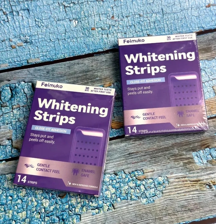 Two boxes of Feimuko Whitening Strips on a textured blue and gray surface