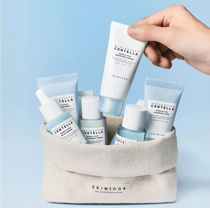 Hand holding a skincare product over a basket filled with Skinfood products against a light blue background

